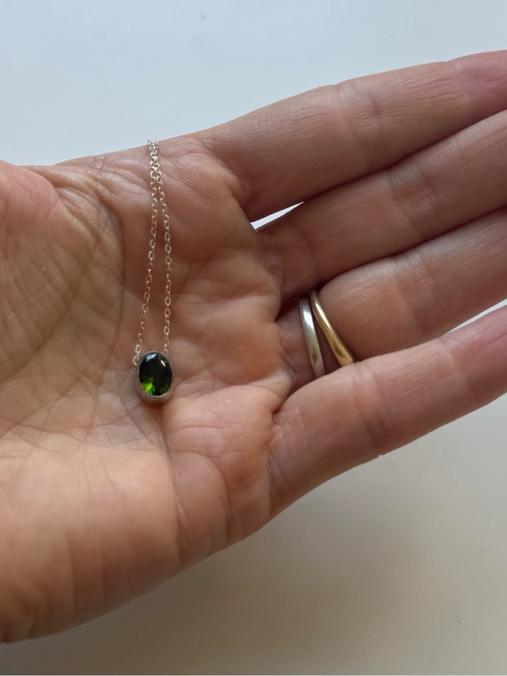 Bezel set green tourmaline pendant on silver necklace